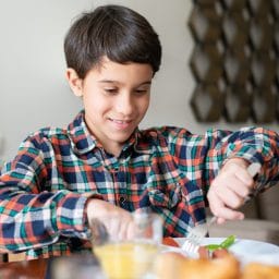 Young boy eating at the table.