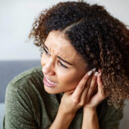 A woman experiencing pain from a ruptured eardrum