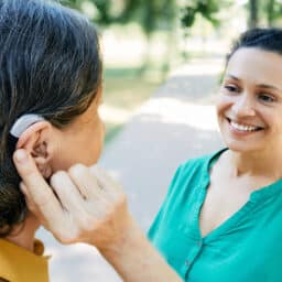 Woman with a hearing aid talking to her friend outside.