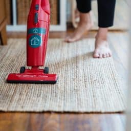 Close-up of a woman vacuuming her carpet at home.