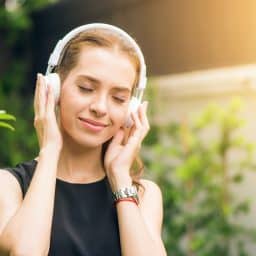 Woman listening to headphones outside.