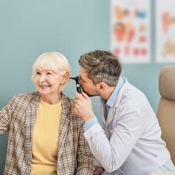 Smiling senior woman having her ears examined at a hearing clinic.