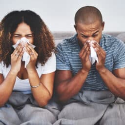 Couple with allergies sneezing on the couch